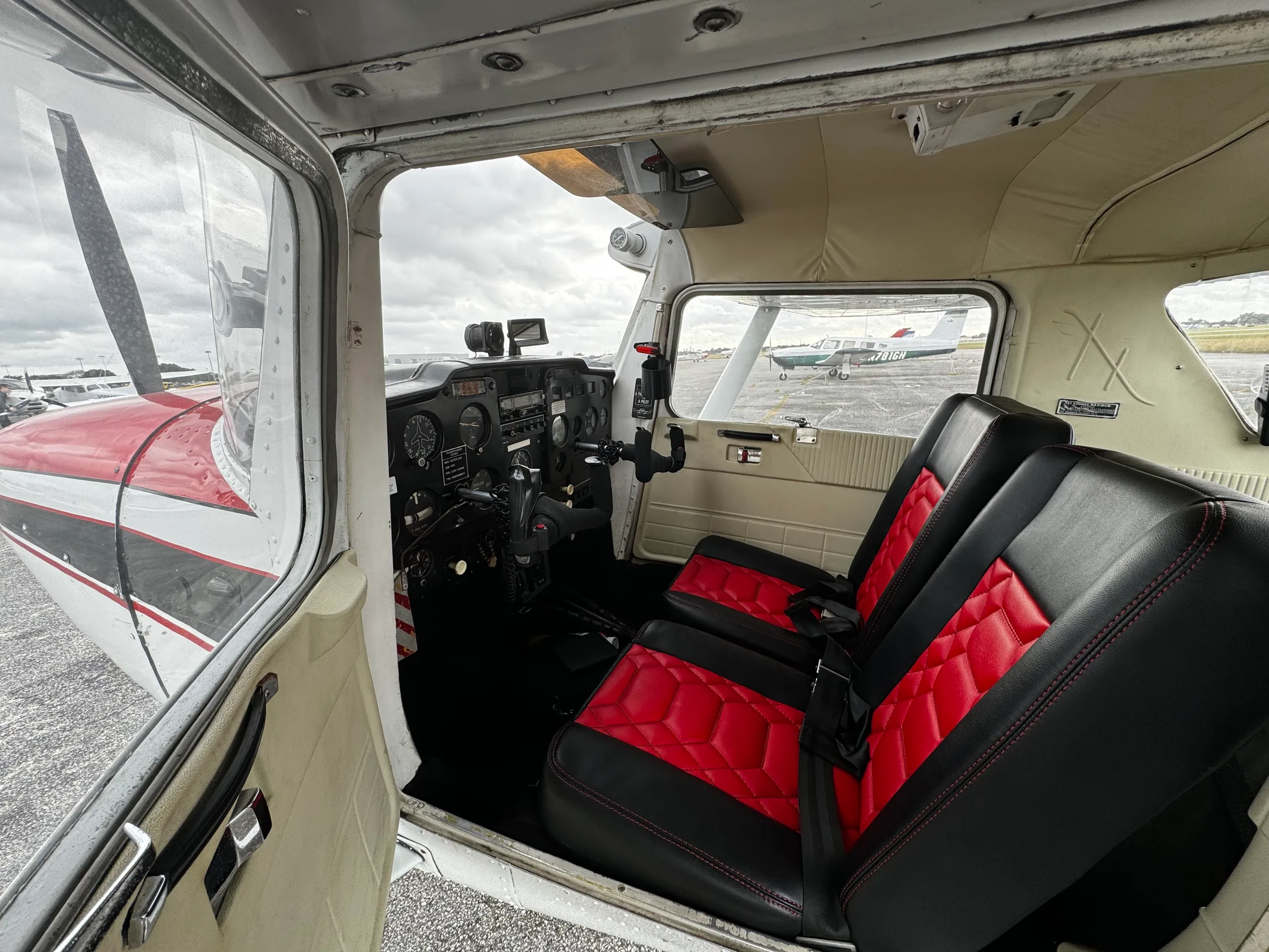 View into the cabin of a Cessna 172, N3640J, showing red and black quilted seats and the instrument panel.