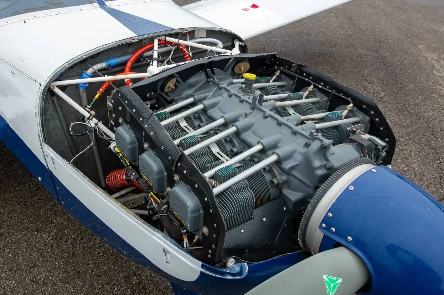 The exposed engine compartment of the blue and white aircraft, showing the engine cylinders and wiring.