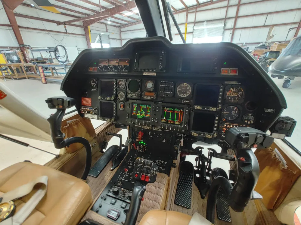 The cockpit of a helicopter features a complex instrument panel with multiple screens and controls, including the registration N749SD.