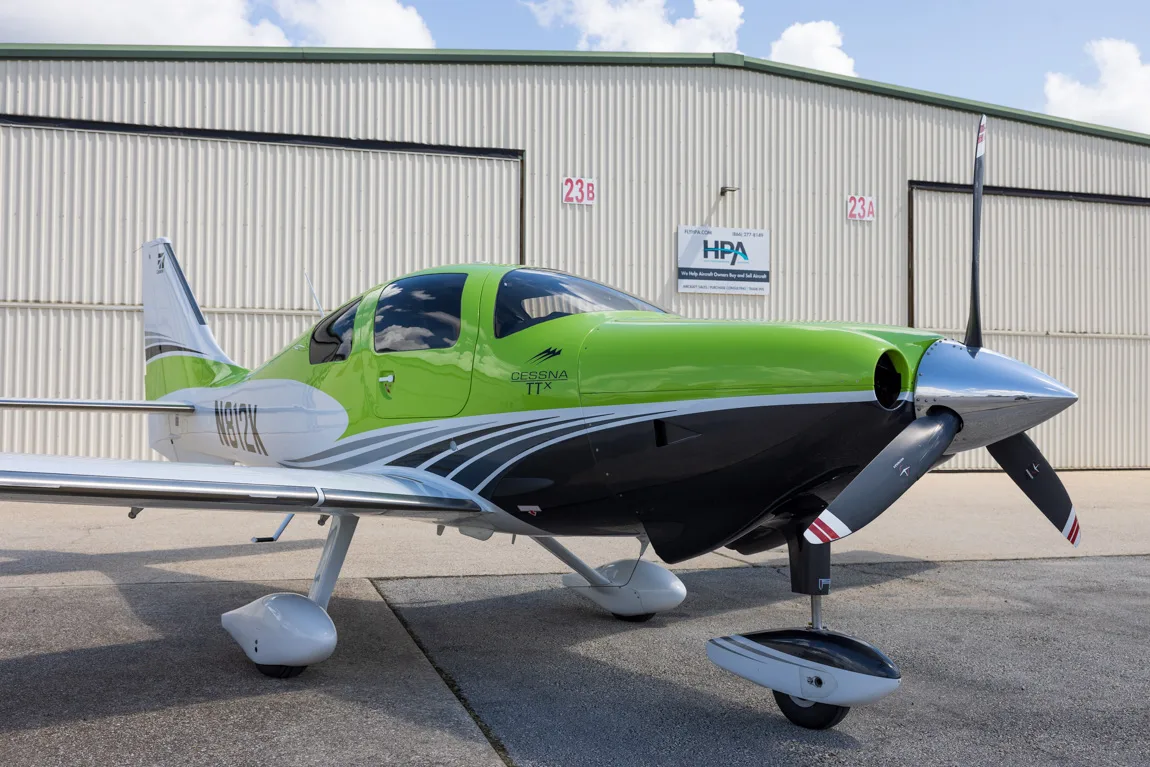 A lime green, white, and black Cessna TTX aircraft with registration N812K parked on an airfield.