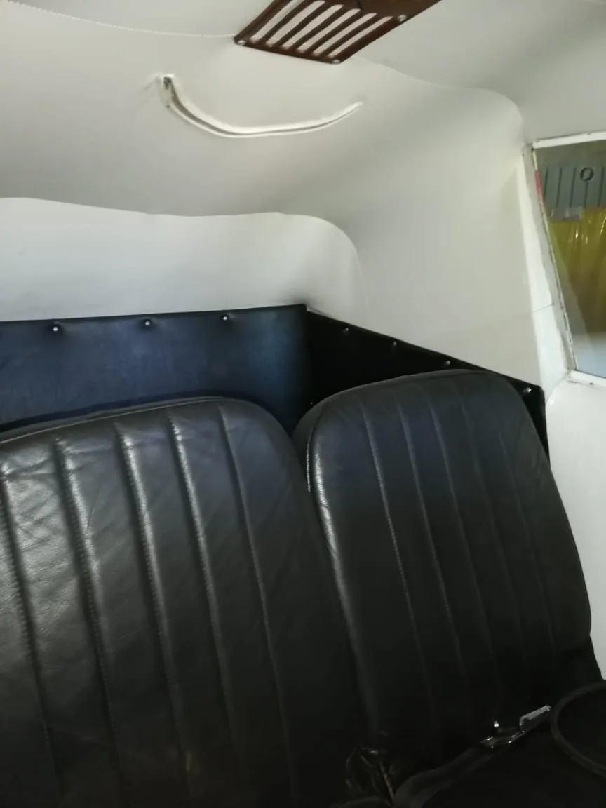 Two black leather aircraft seats in a small cabin with white walls and ceiling.