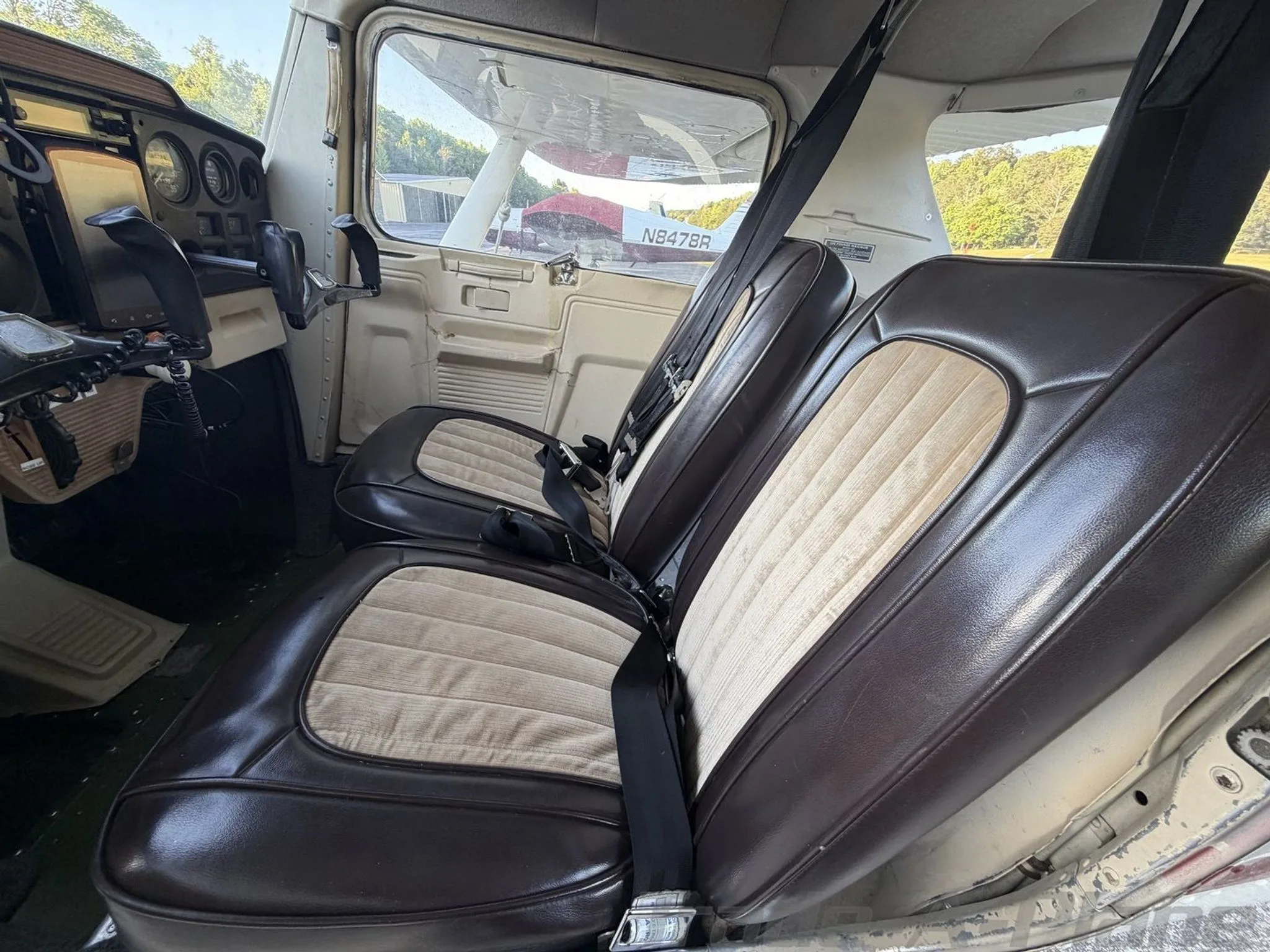 Interior view of the Cessna 172 cabin showing brown and tan upholstered seats and the cockpit area.
