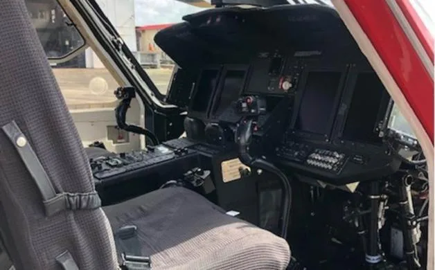 The cockpit of a helicopter shows the instrument panel, controls, and pilot's seat.
