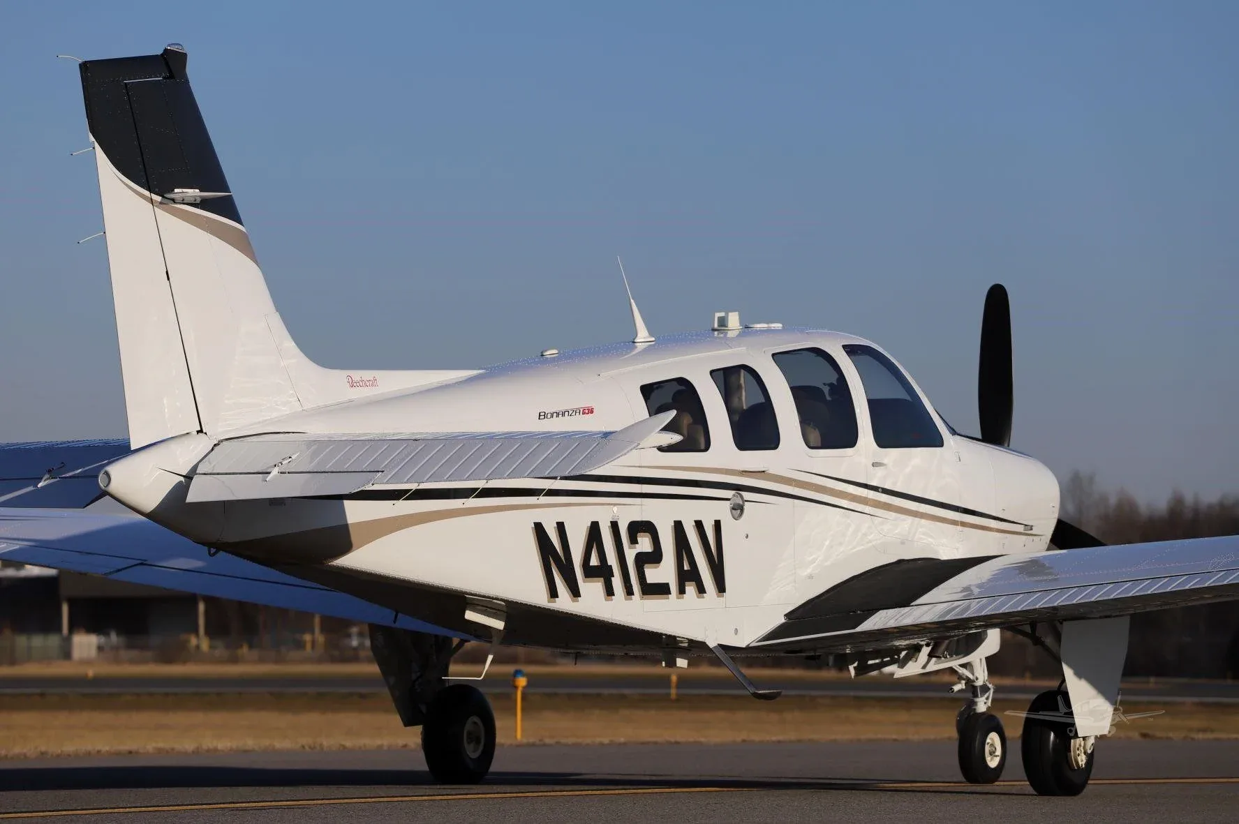 A white Beechcraft Bonanza G36, registration N412AV, seen from the rear-right on a runway.