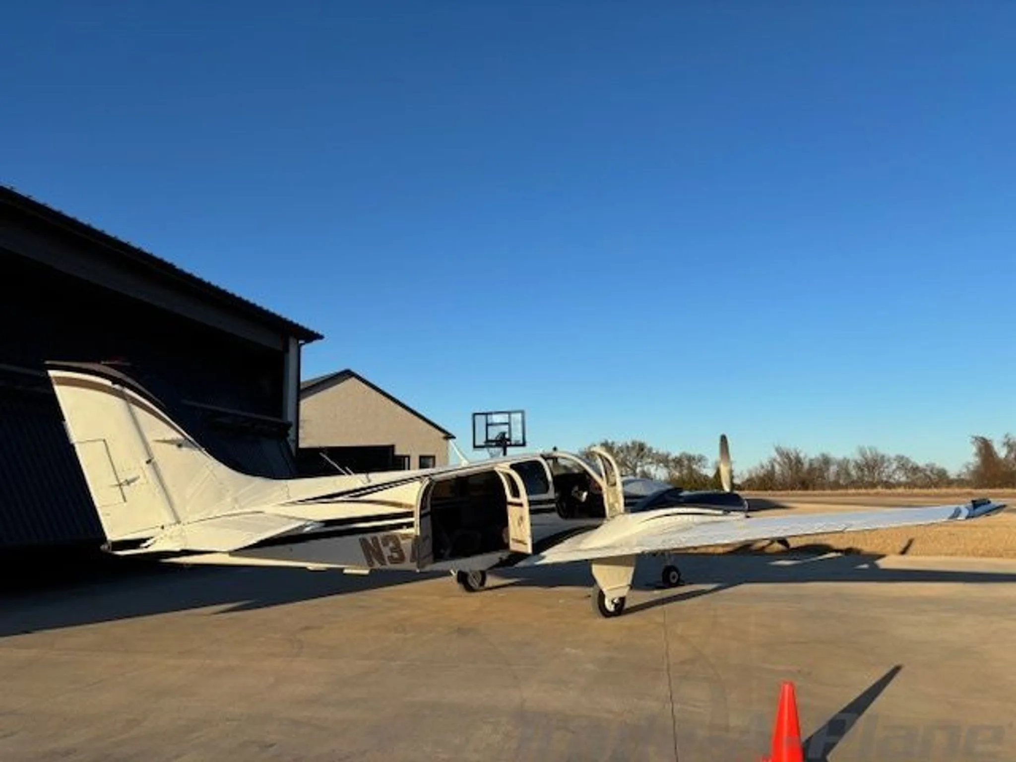 A white and black twin-engine aircraft with gold stripes and open passenger doors, viewed from the rear-left.