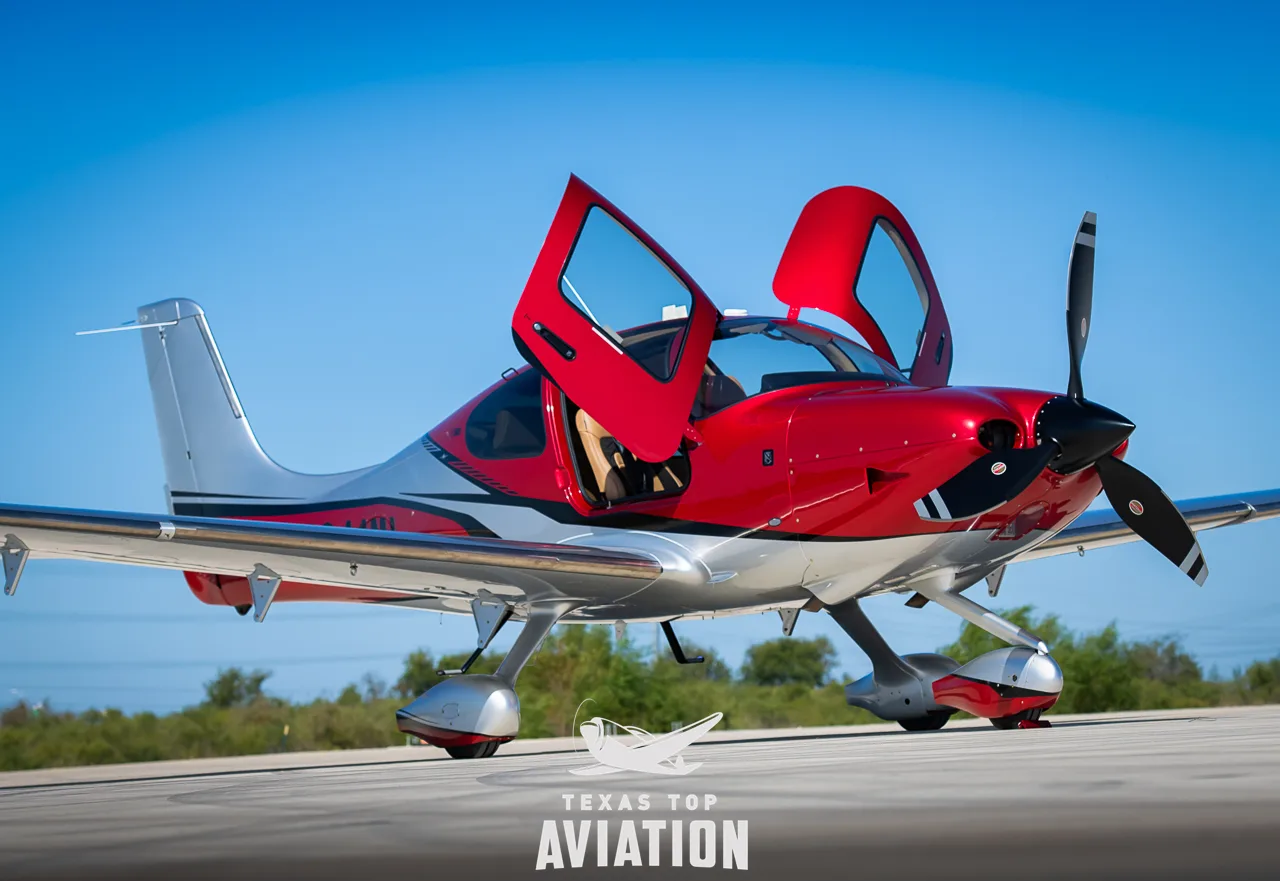 A red and silver Cirrus SR22T GTS aircraft with both gull-wing doors open on an tarmac.