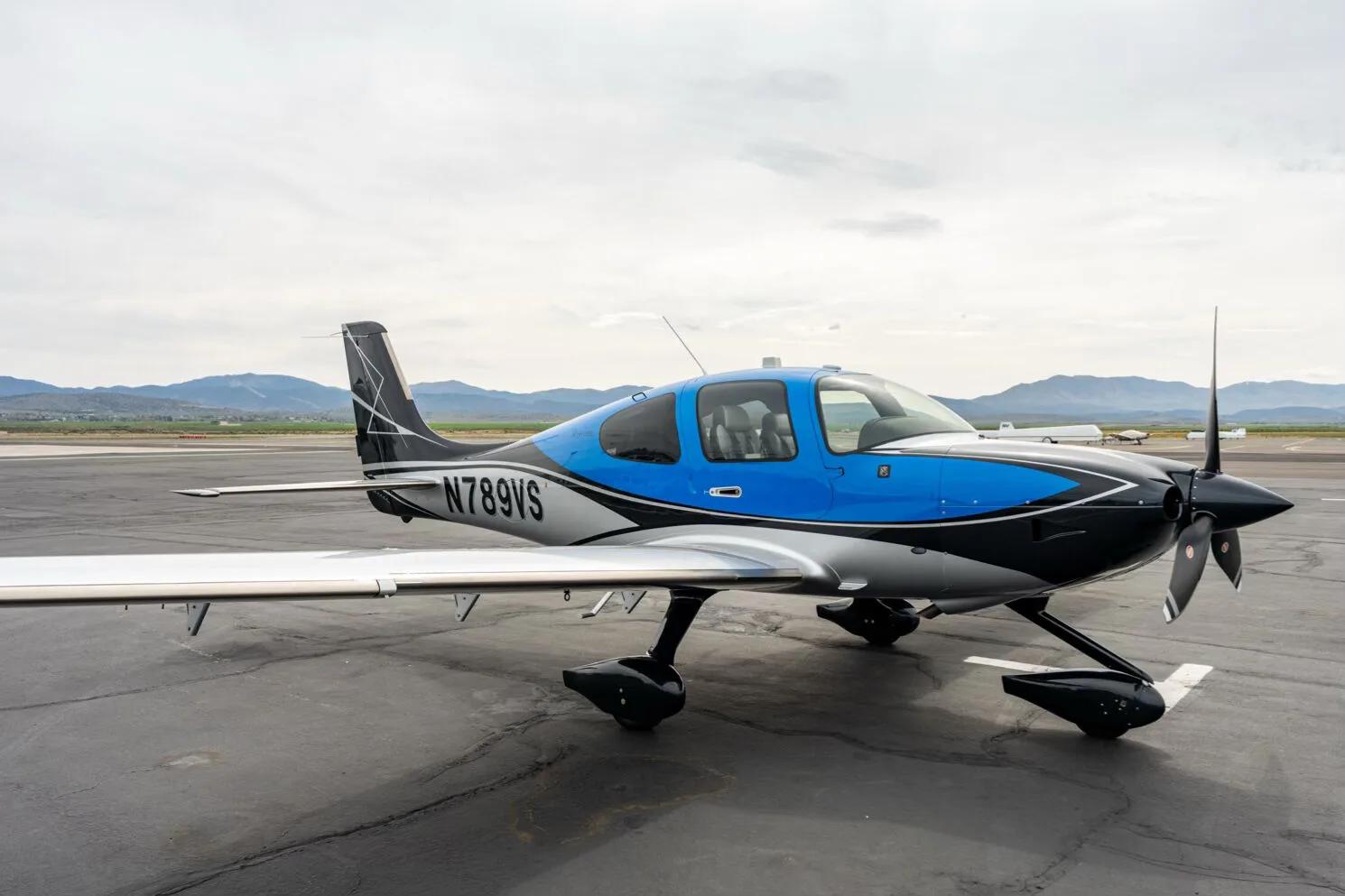 Side view of a black, blue, and silver single-engine aircraft with registration N789VS on an airfield.