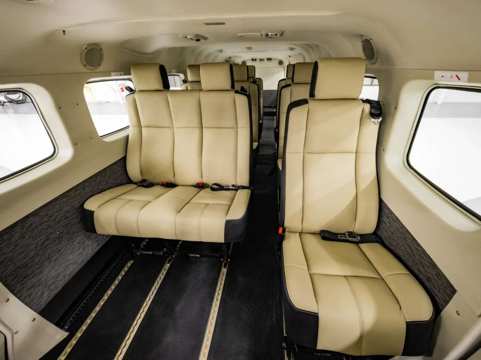 The aircraft cabin interior features two rows of beige and black passenger seats.