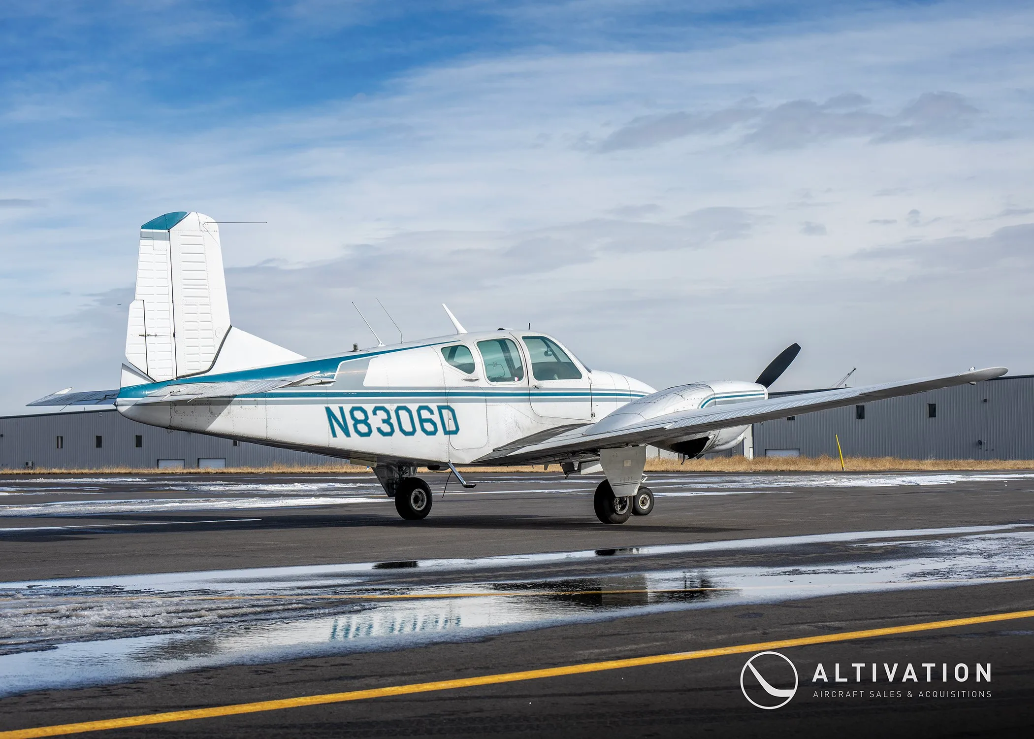 Left side view of a white and blue twin-engine propeller aircraft with registration N8306D on the fuselage.
