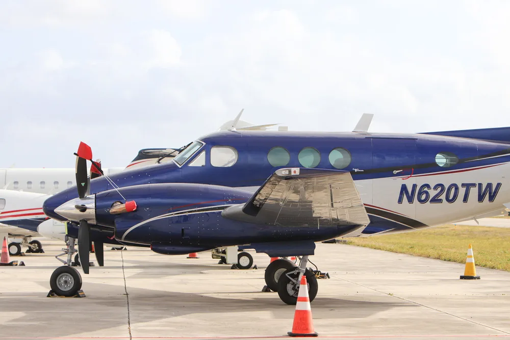 A blue and white twin-engine turboprop aircraft, N620TW, parked on a tarmac with orange cones.