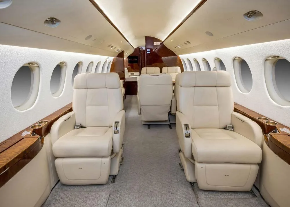 The luxurious interior cabin of a business jet with cream leather seats and polished wood accents.