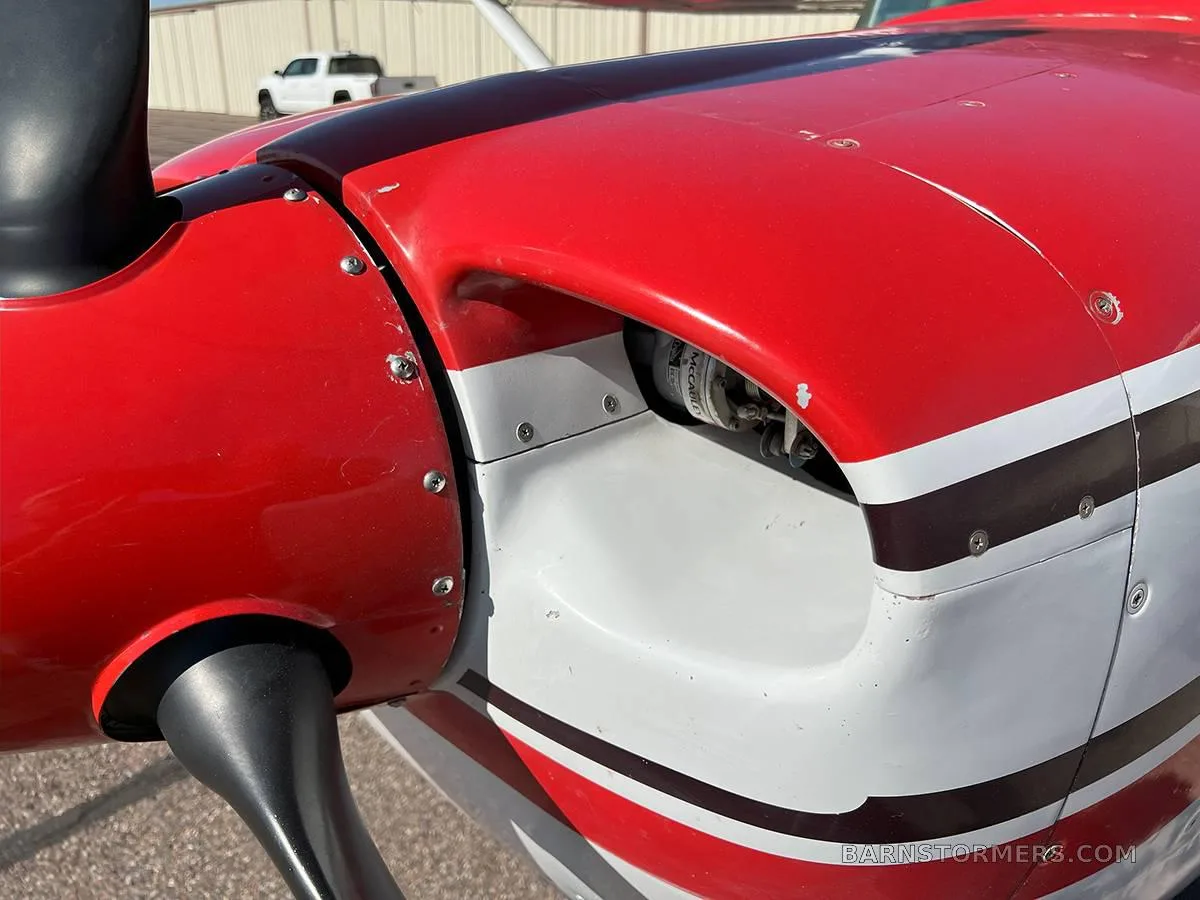 A close-up view of the red and white engine cowling and propeller hub of a Cessna Skylane II.