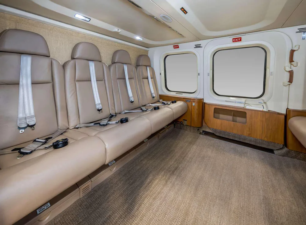 The interior cabin of a helicopter featuring tan leather seats and a beige carpet.