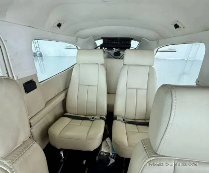 The cream-colored leather interior cabin of a small aircraft, showing two rows of seats.