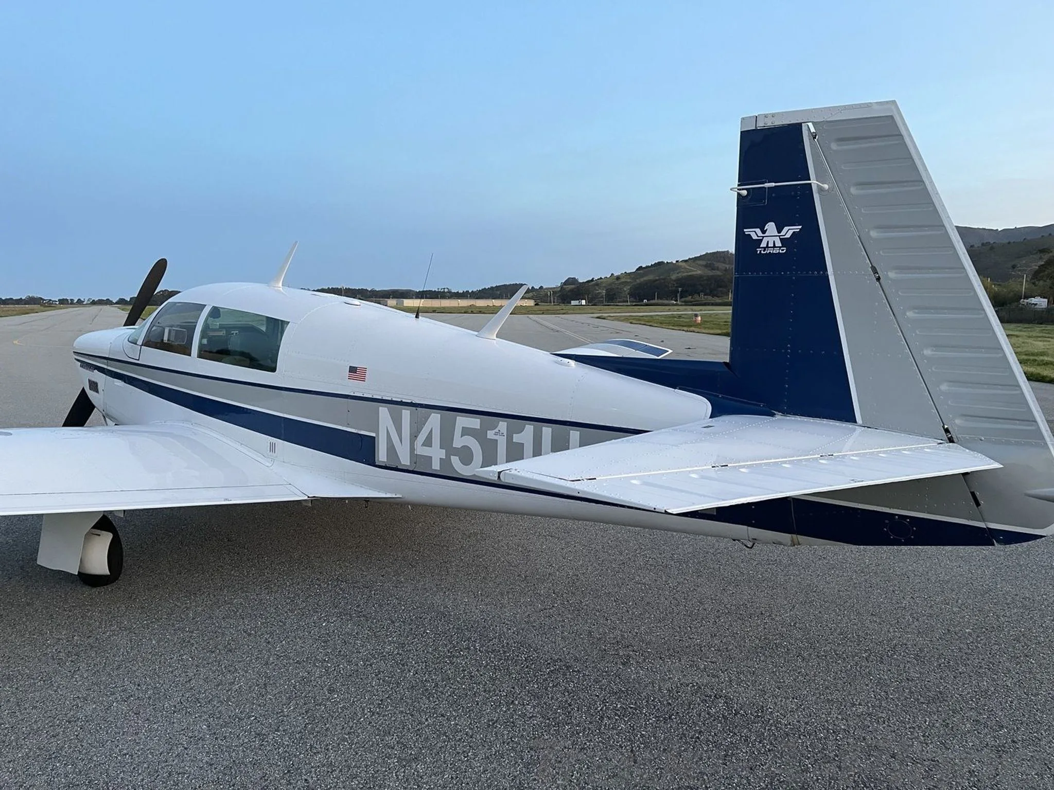 A close-up view of the tail and rear fuselage of the white and blue aircraft N4511H on an airfield.
