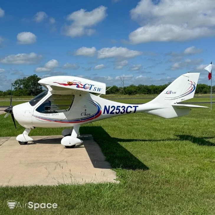A white Flight Design CT Light Sport aircraft, N253CT, is seen from the side on a concrete pad with grass and a Texas flag in the background.