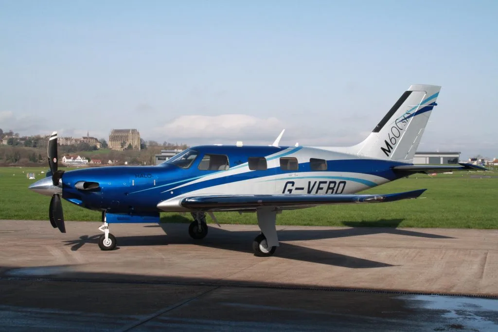 A side view of a blue and silver Piper M600SLS aircraft (G-VERO) parked on an airfield tarmac.
