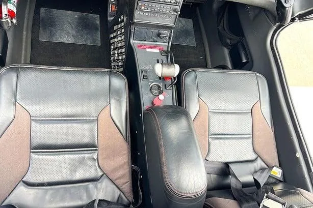 The front seats and center console of a Cirrus SR22 cockpit, featuring black leather seats with brown accents.
