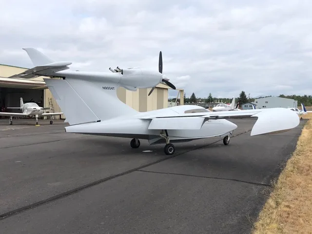 The white Searey amphibian aircraft, N9004T, is parked on an asphalt runway, viewed from the rear-left.