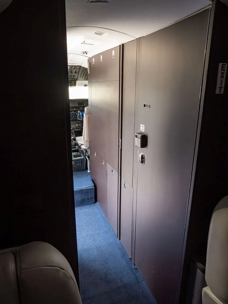 View of the aircraft interior with storage cabinets and cockpit in the distance.