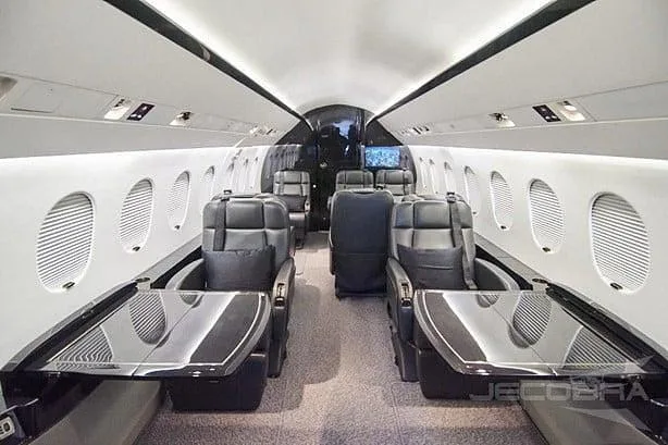 The luxurious interior of an aircraft cabin featuring black leather seats and polished tables.