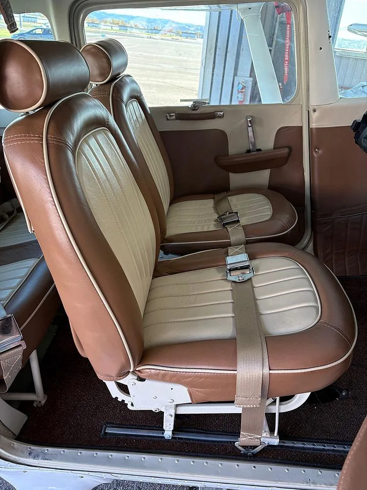 A view of the aircraft's two-tone brown and cream leather seats from inside the cabin, with an airfield visible outside.