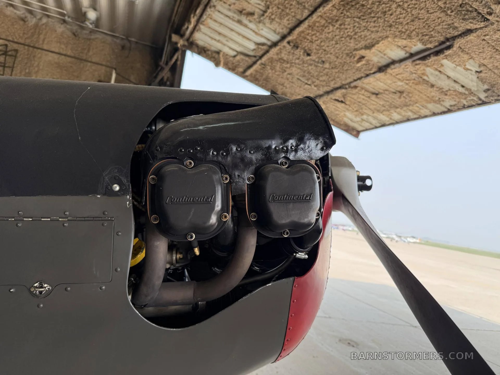 A close-up view of the aircraft's Continental engine and propeller, partially exposed under the cowling.