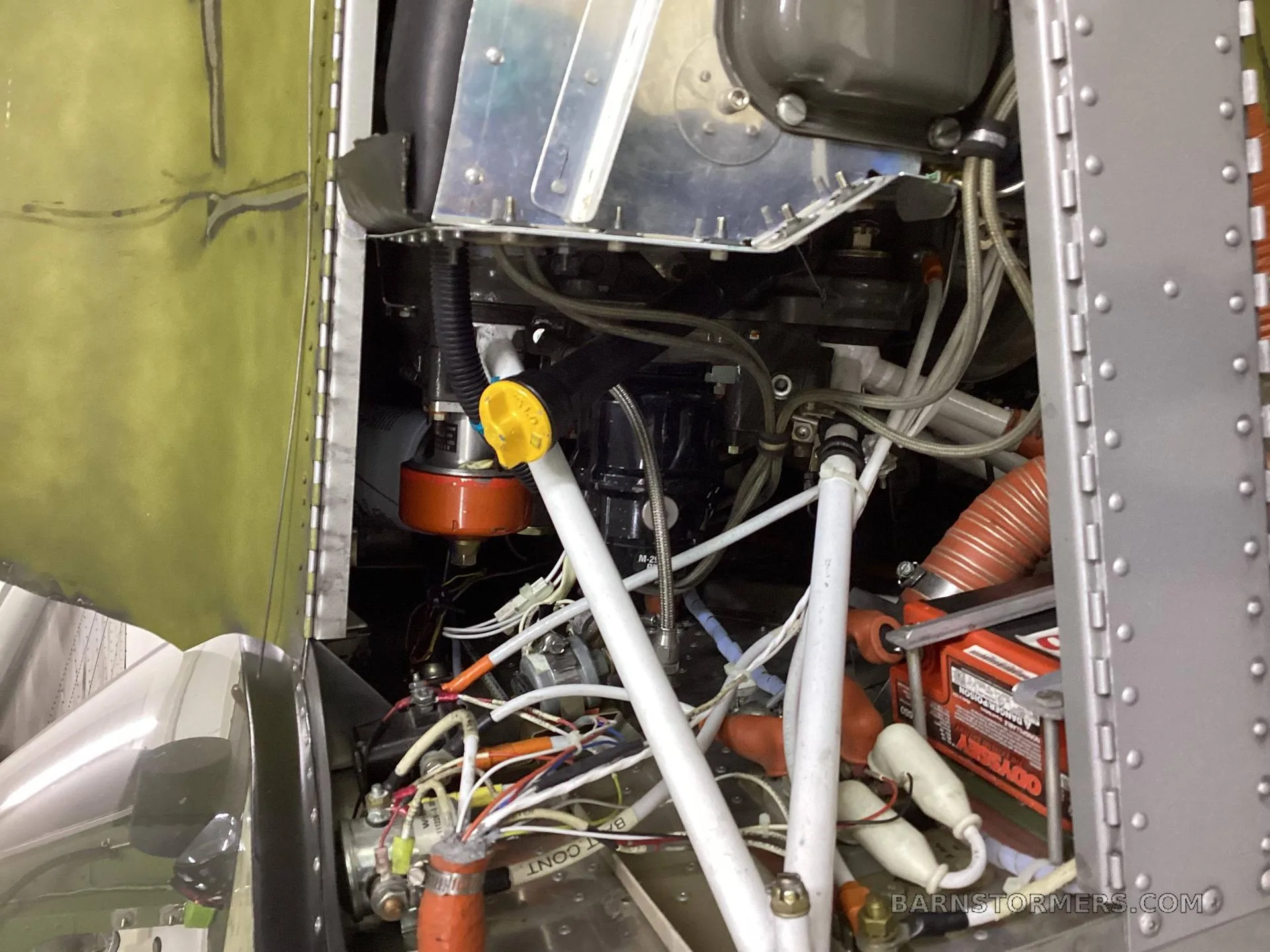 A close-up view of the aircraft's internal components, including wiring, hoses, and mechanical parts, with a yellow cap visible.