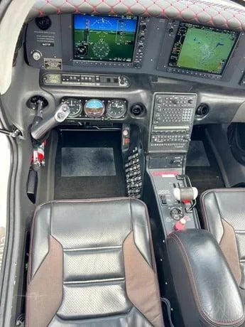 The cockpit of a Cirrus SR22, showing the instrument panel with dual displays and the front pilot seats.