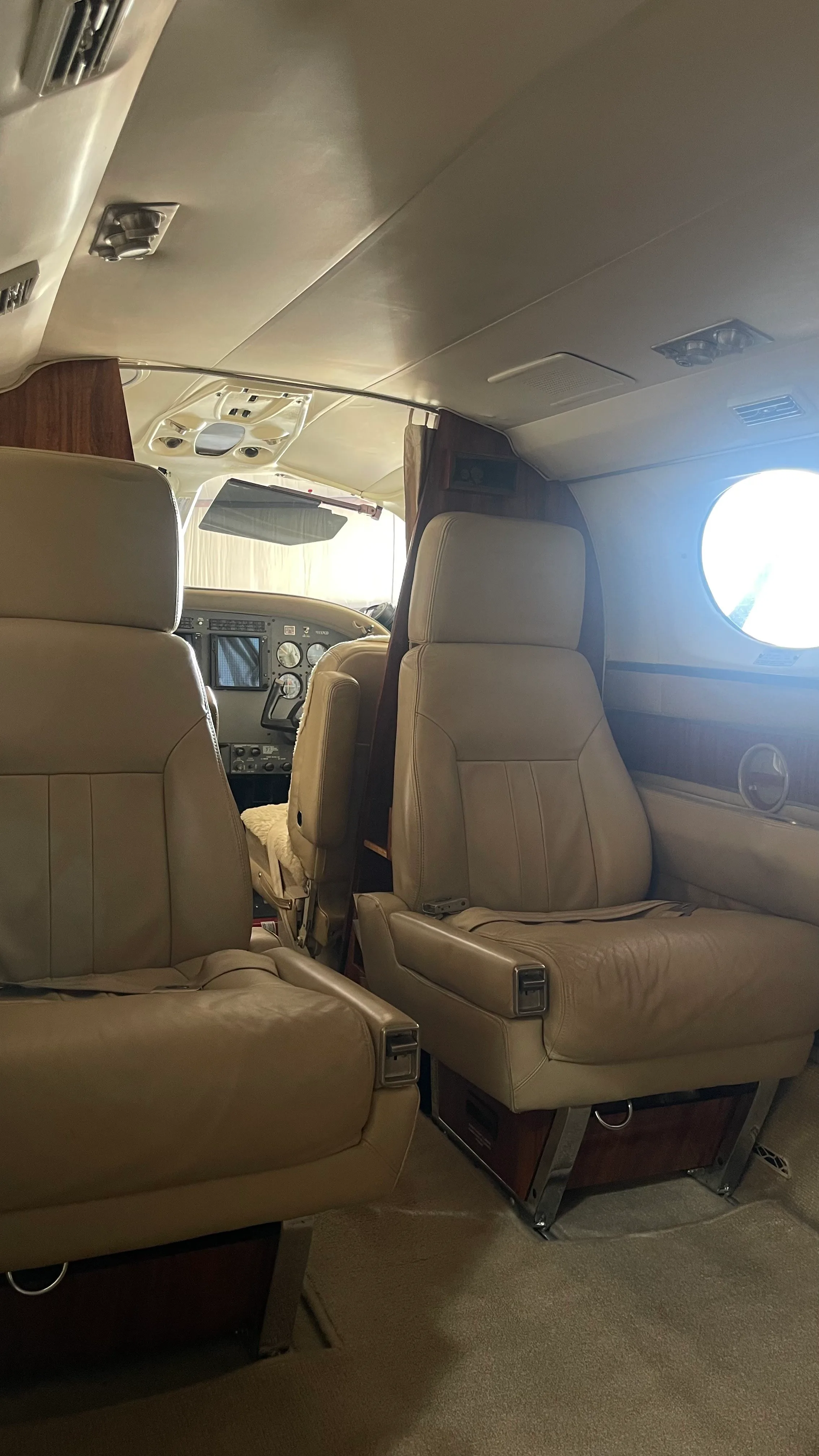 View from the rear of the aircraft cabin looking forward towards the cockpit, showing tan leather seats.