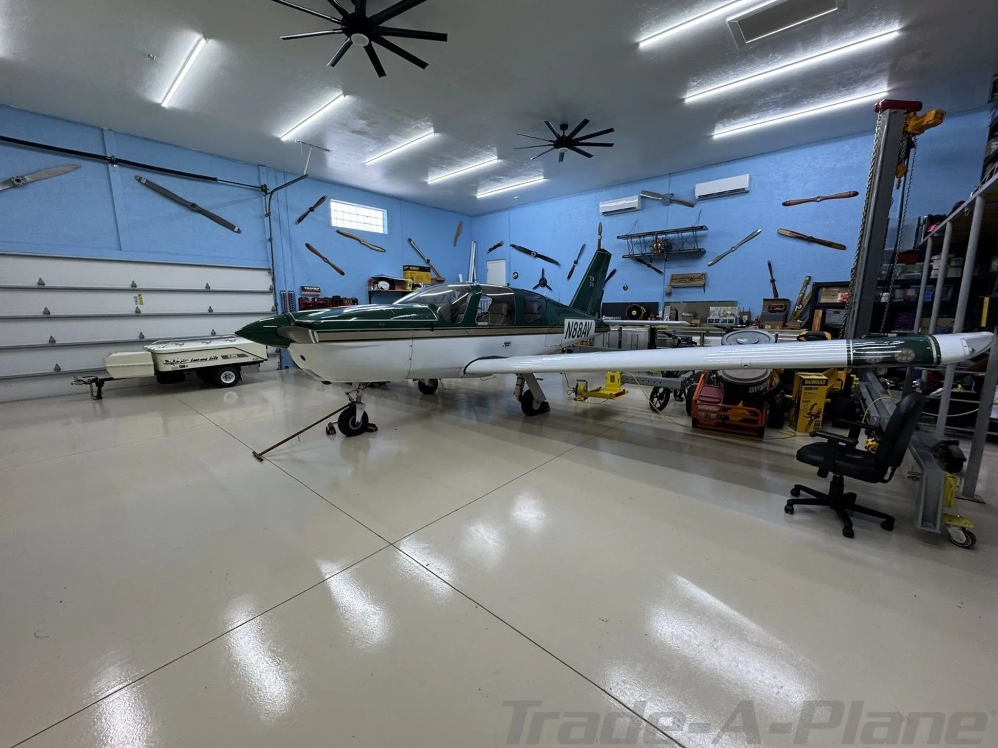 A side view of a green and white single-engine aircraft (N88AV) parked inside a hangar.