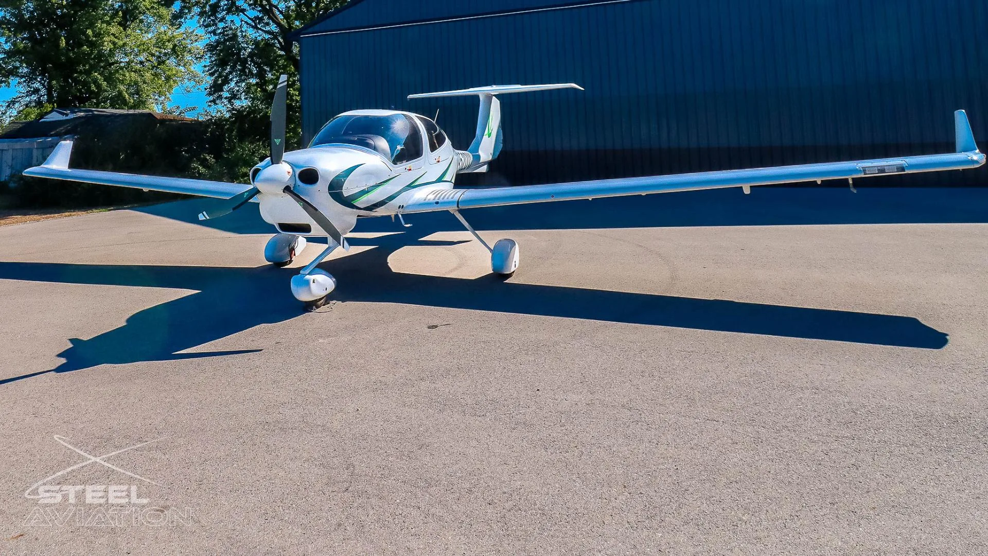 Front view of a white Diamond DA40 aircraft with green accents and registration N952DW parked on an asphalt surface.