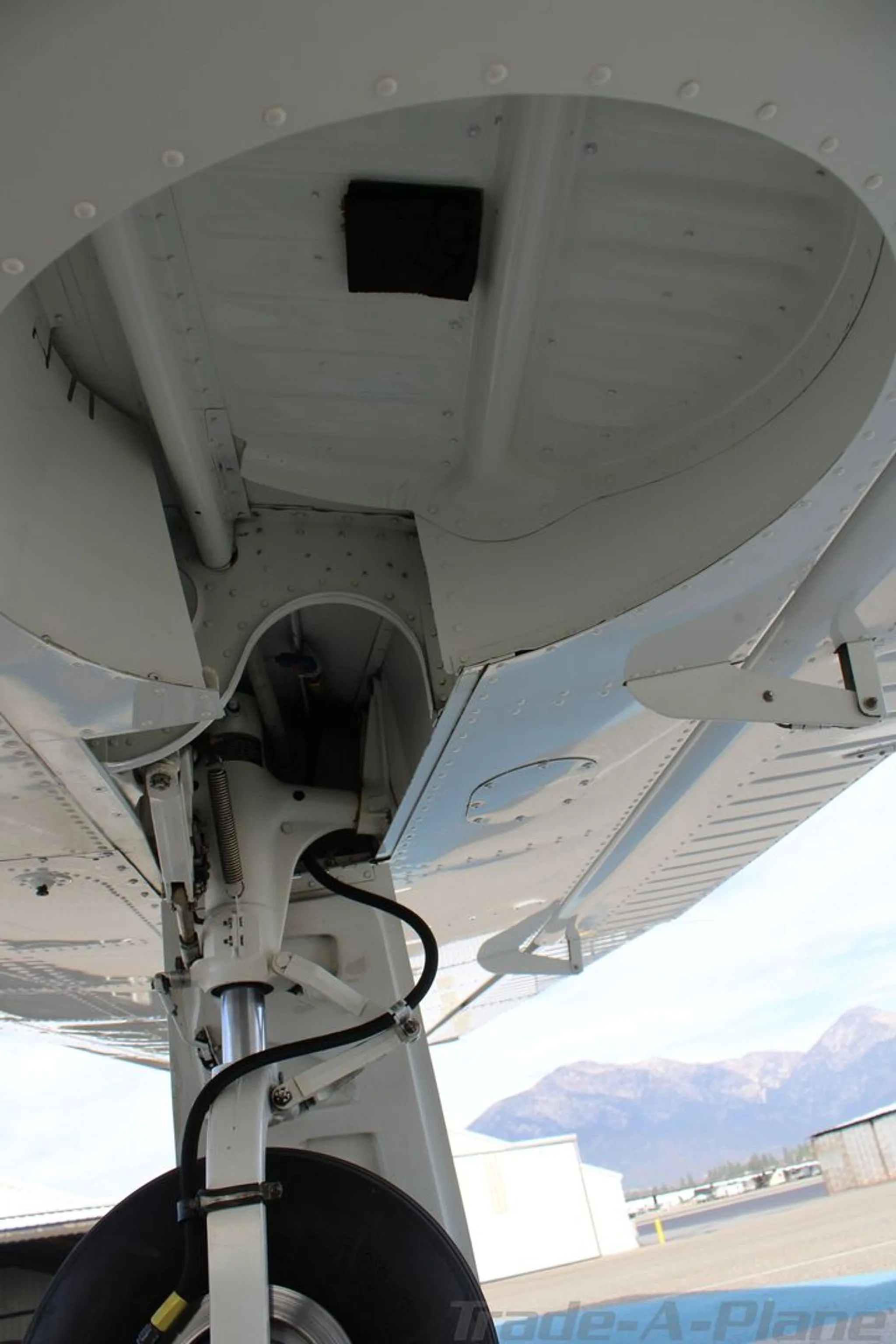 A close-up view of the white main landing gear strut and wheel well of the Piper aircraft.