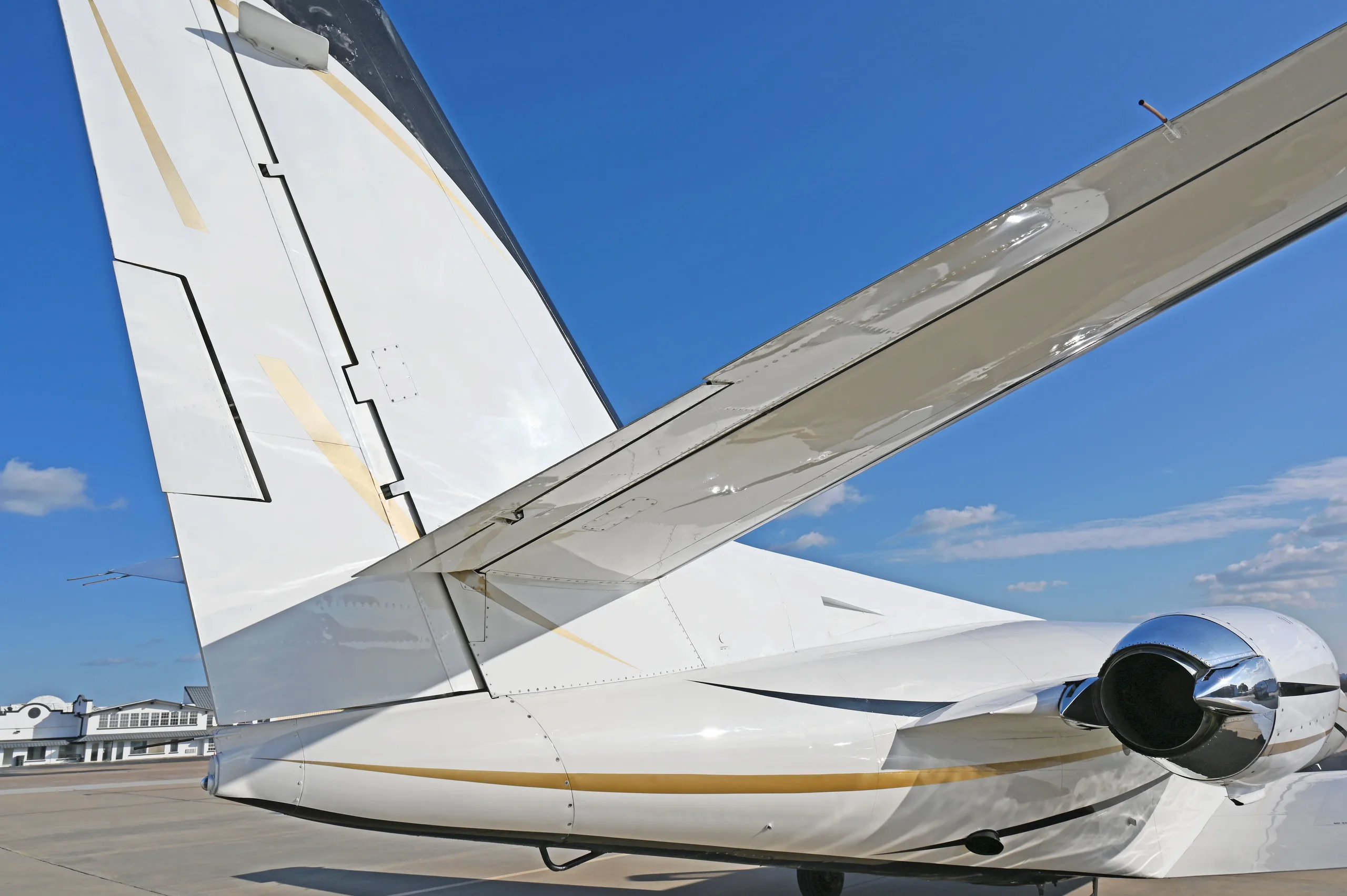 A close-up view of the tail and right engine of a white business jet with black and gold accents.