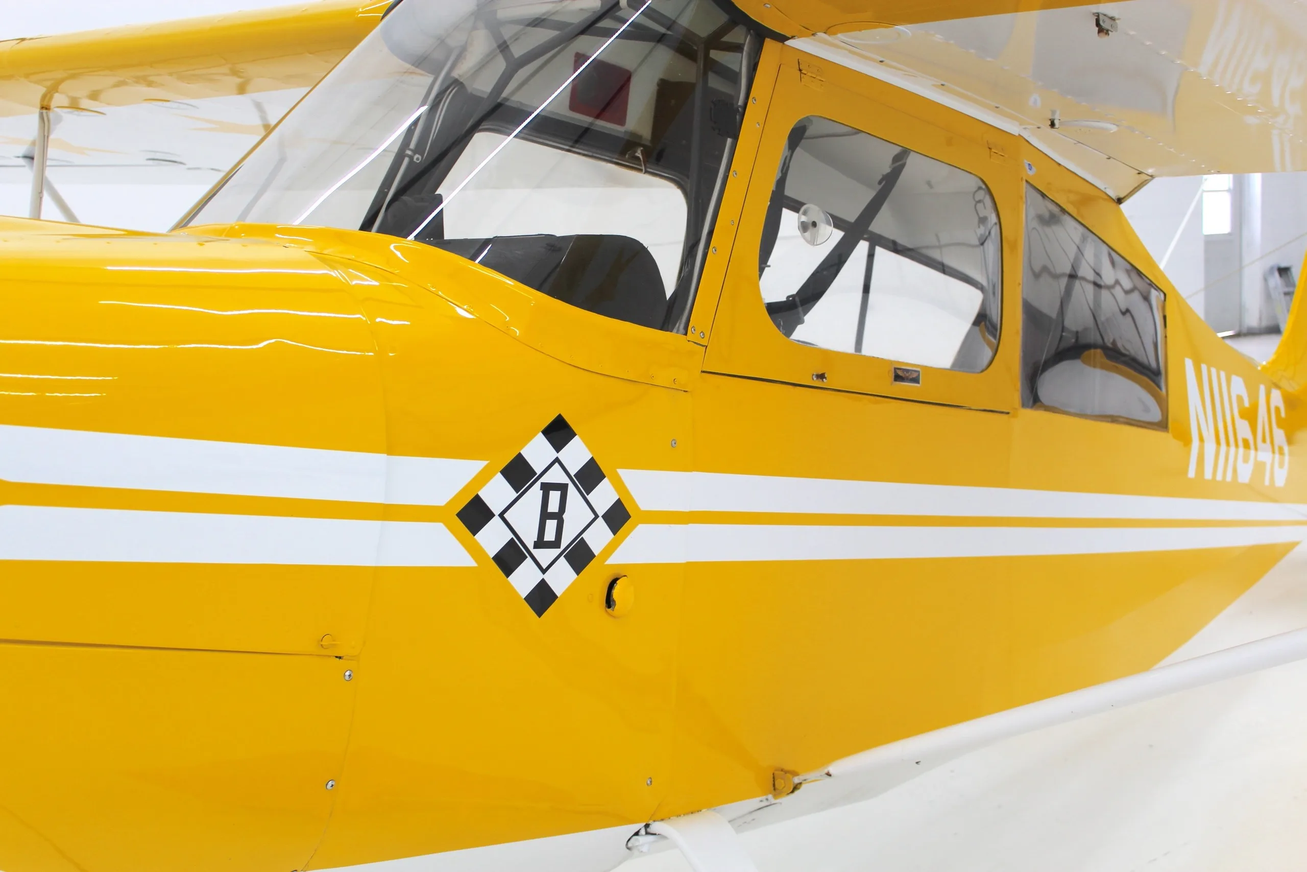 A close-up of the yellow fuselage of N11646, showing the checkerboard 'B' emblem and white stripe.