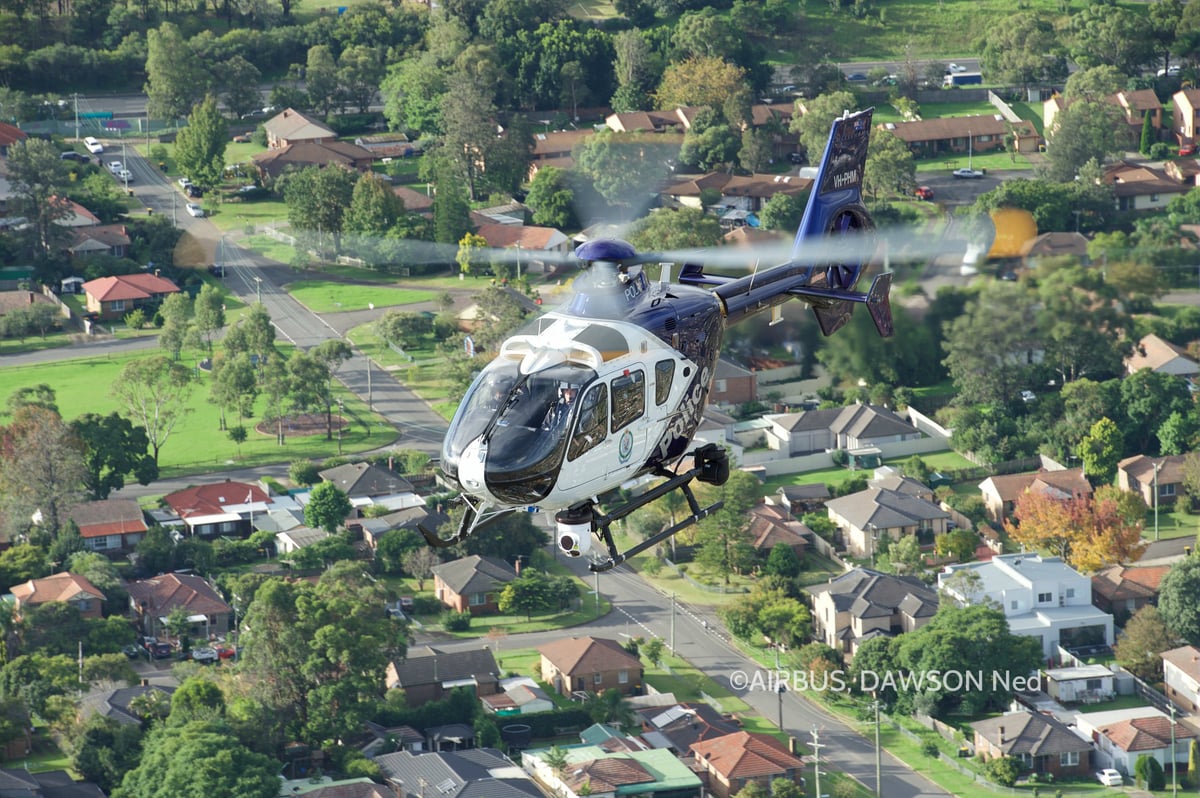 A police helicopter flying over a suburban neighborhood.