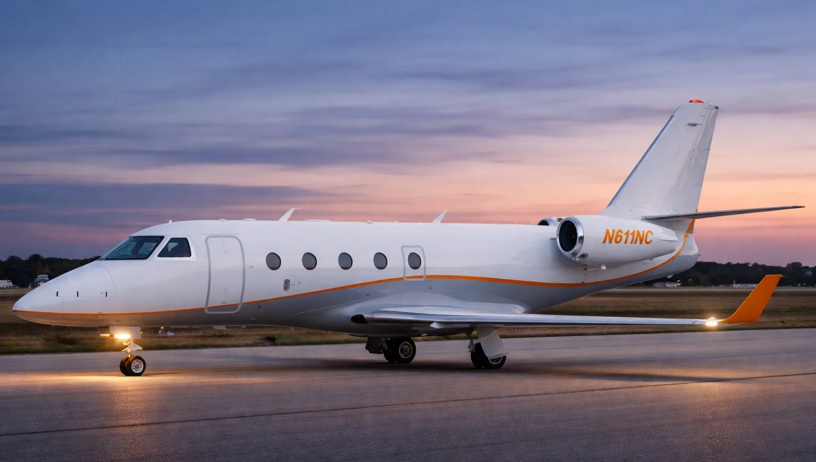 A white business jet with orange and grey stripes, tail number N611NC, parked on a tarmac at sunset.