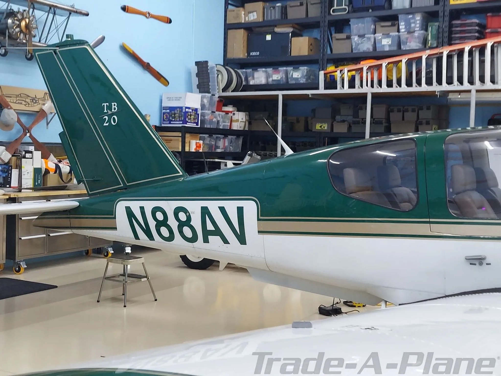 A close-up of the tail and rear fuselage of the green and white aircraft (N88AV) inside a hangar.