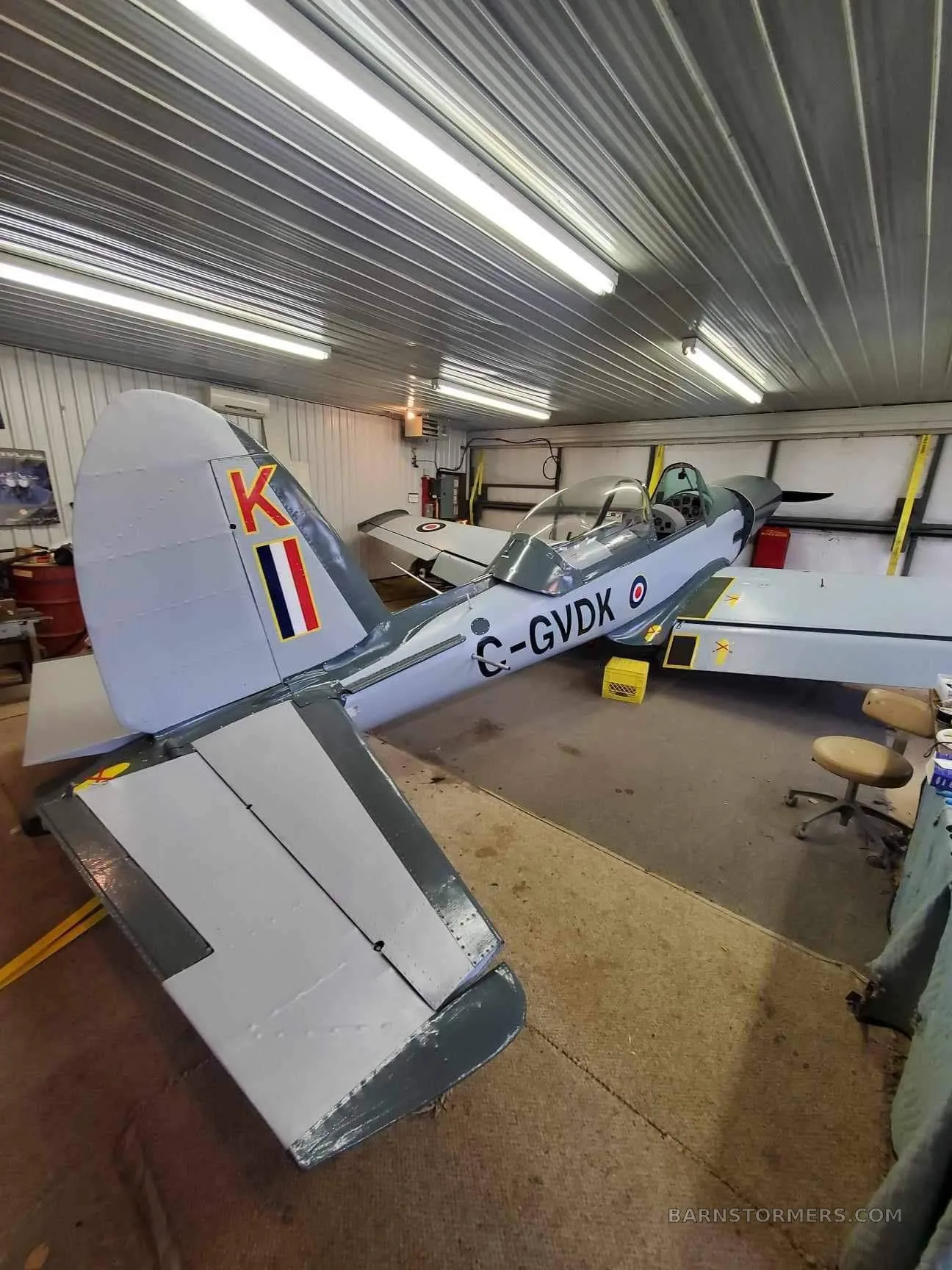 A light grey single-engine aircraft with Canadian registration C-GVDK parked inside a well-lit hangar.