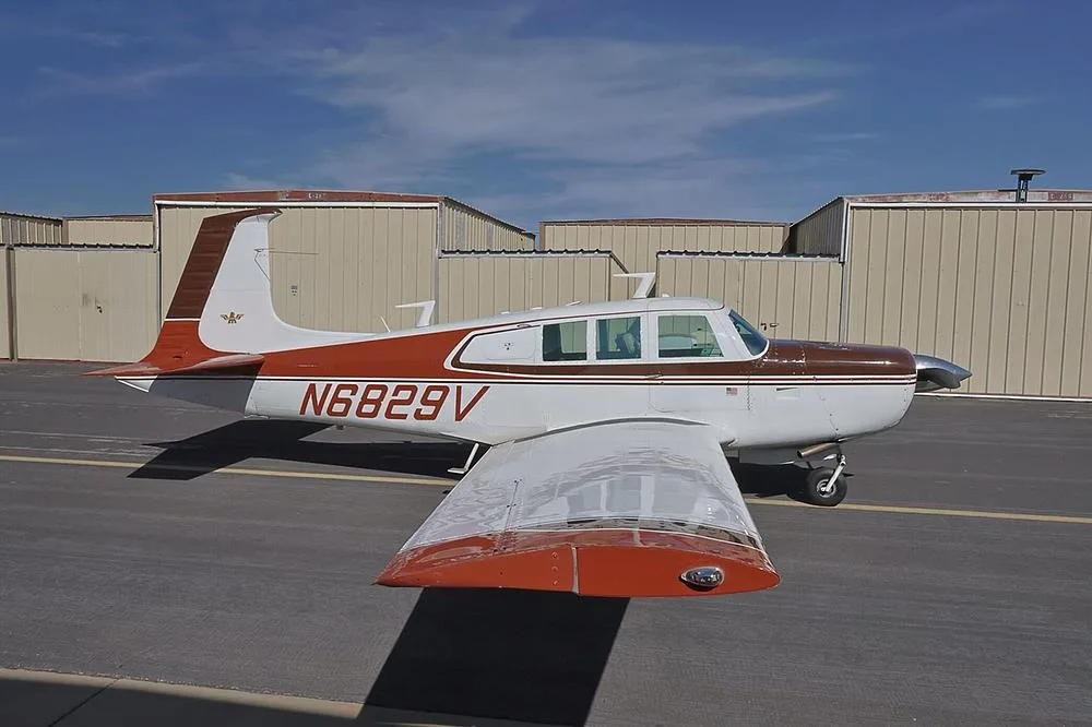 A side profile of the brown and white single-engine aircraft, N6829V, parked on an asphalt ramp.