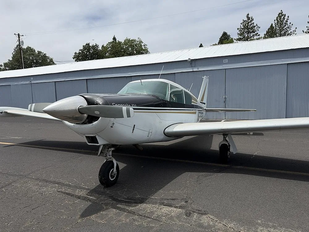 Front view of a white and black Piper Comanche 250, registration N5365P, parked on an airfield.