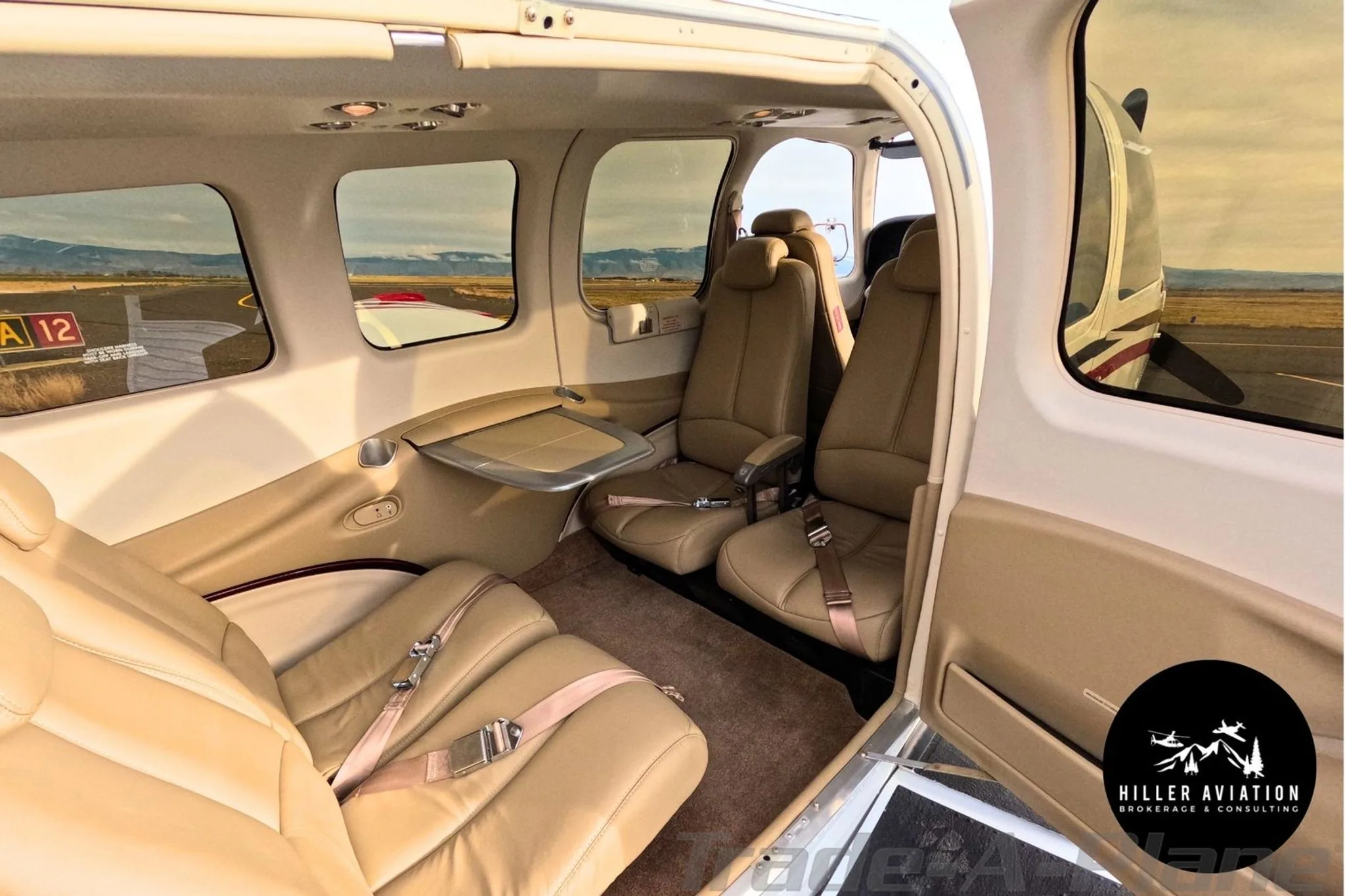 Interior view of the tan leather cabin seats and fold-out table in a Beechcraft Bonanza G36.