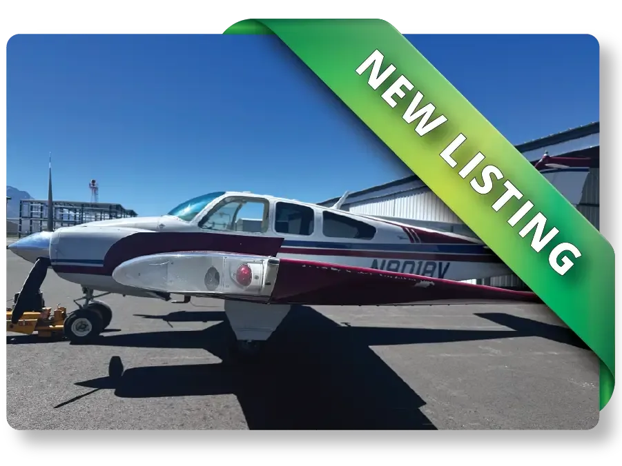 A white and maroon propeller aircraft, registration N101AV, parked on an asphalt ramp with a hangar in the background under a clear blue sky.