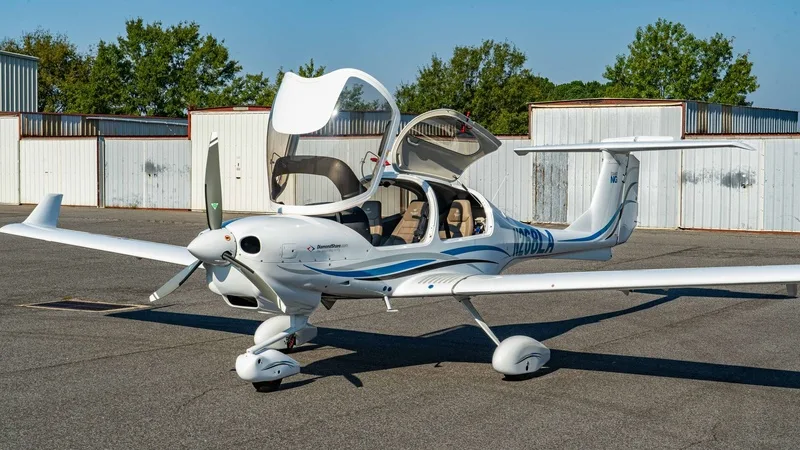 A white Diamond DA40 aircraft with blue and grey stripes, registration N200LA, parked on an tarmac with its canopy open.