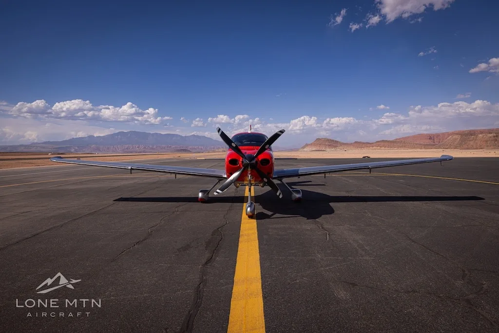 A head-on view of a red and silver Cirrus SR22T aircraft (N605FB) on an airfield with a yellow centerline.
