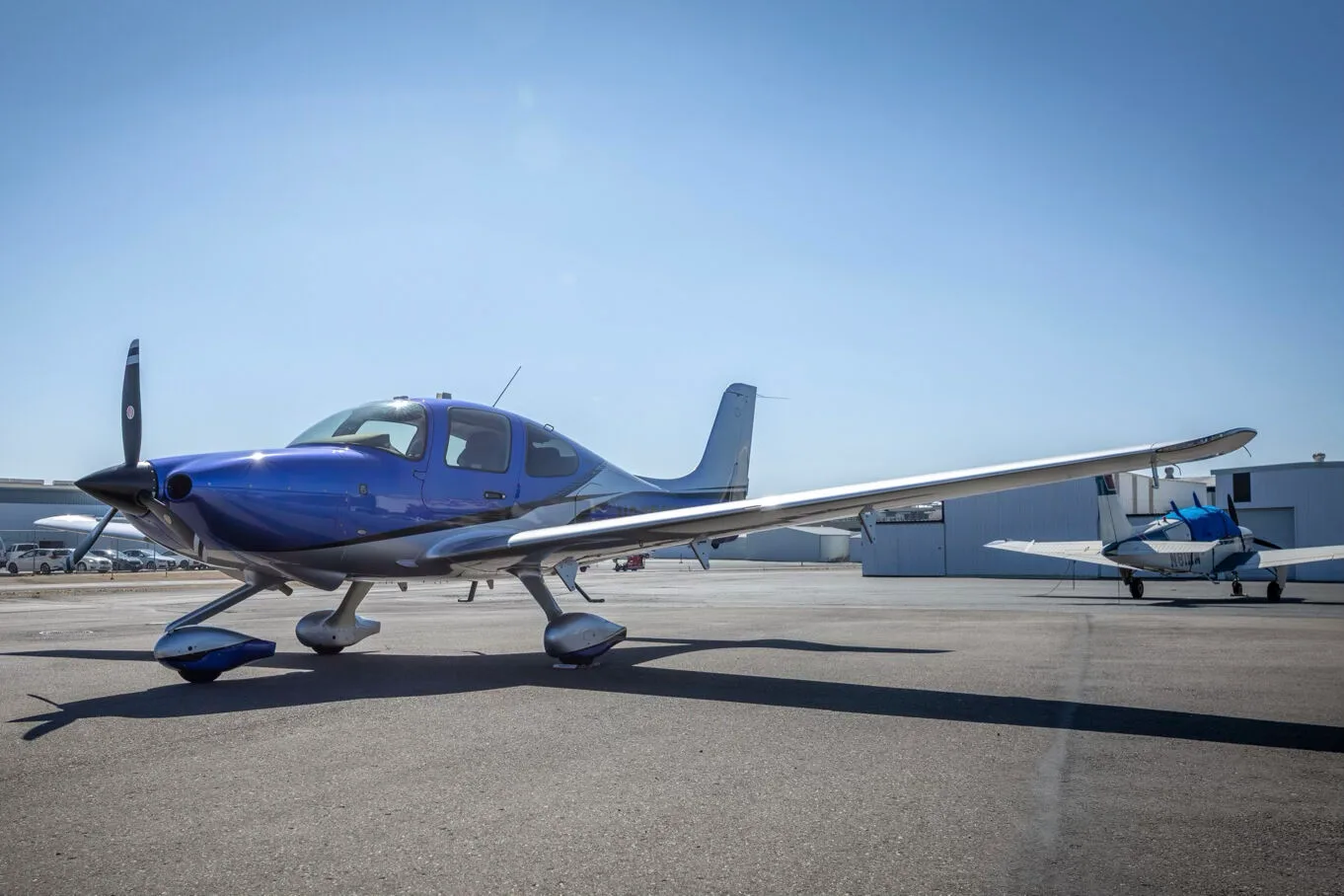 A three-quarter front view of the blue and silver Cirrus SR22 aircraft, N275MG, on an airport tarmac.