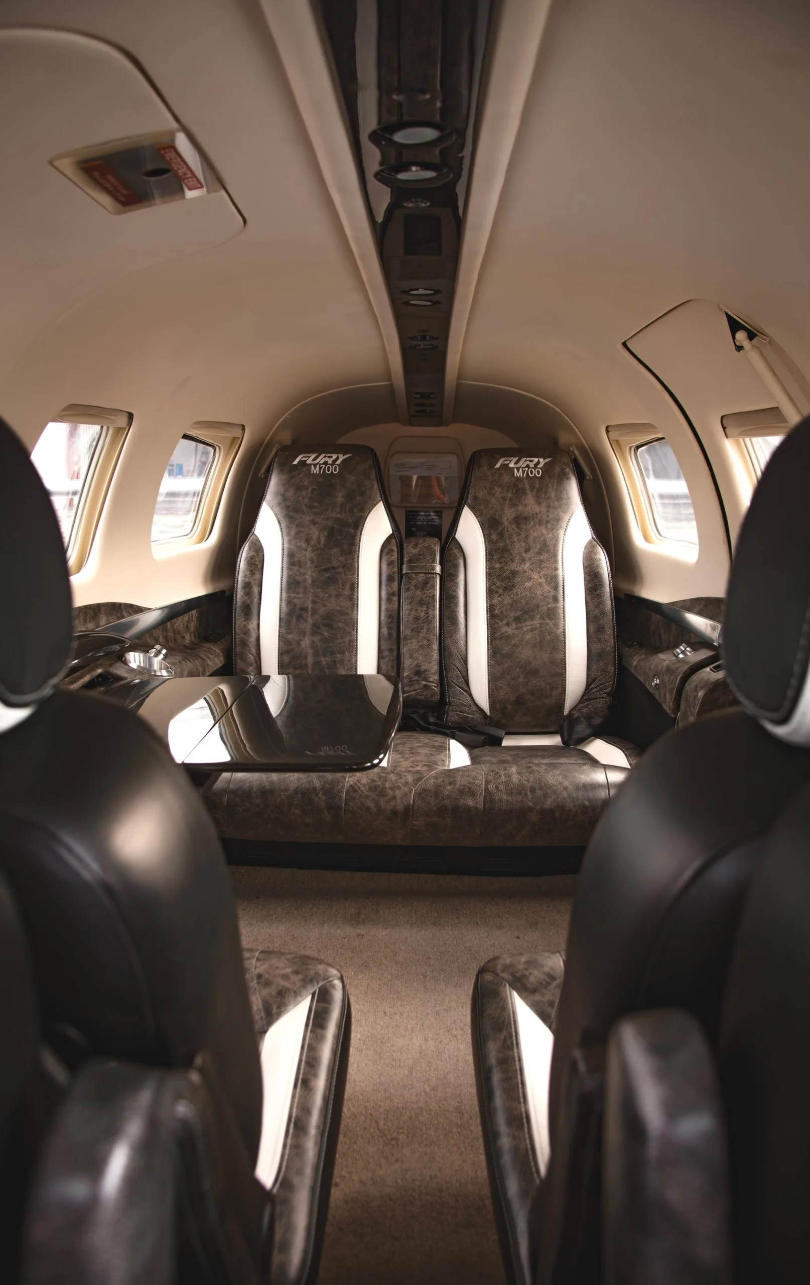 The interior of the Fury M700 aircraft with leather seats and a table.