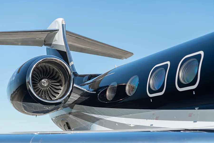 A close-up view of the engine and windows of a dark blue and white Gulfstream G650 business jet, tail number N609JS.