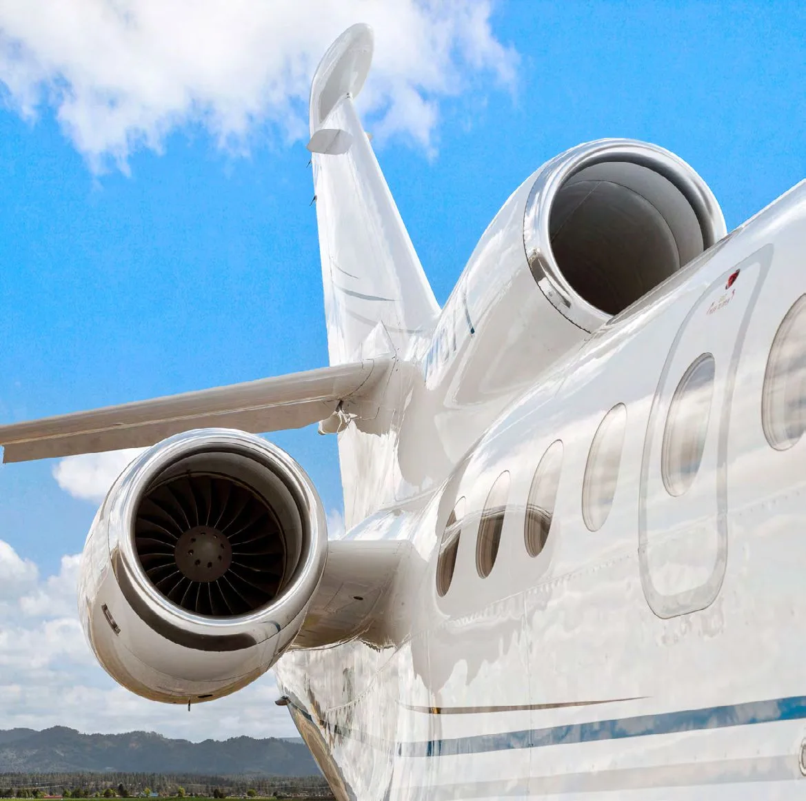A close-up view of the rear fuselage, two engines, and tail of a white business jet.