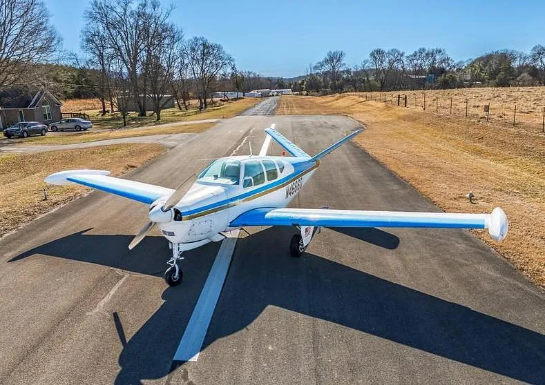 A white and blue single-engine aircraft with registration N4666D viewed from the front on an asphalt runway.
